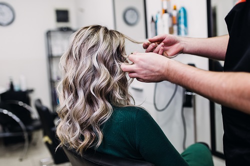 Frau die ihrer Kundin die Haare lockig macht