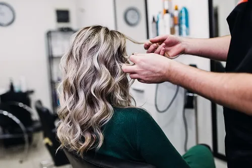 Frau die ihrer Kundin die Haare lockig macht
