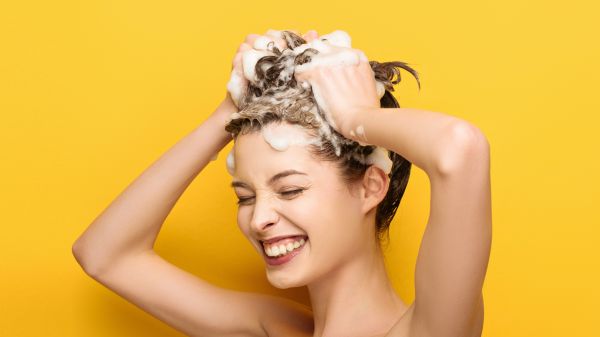 Lachende Frau die sich gerade die Haare shampooniert