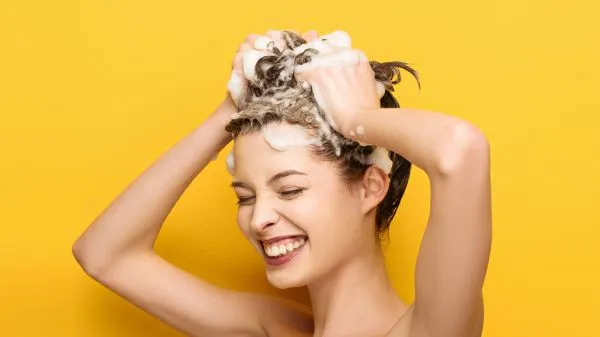Lachende Frau die sich gerade die Haare shampooniert