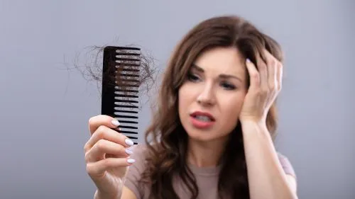 Frau mit Kamm voller Haare in der Hand