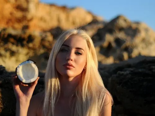 Blonde Frau mit Kokosnuss in der Hand