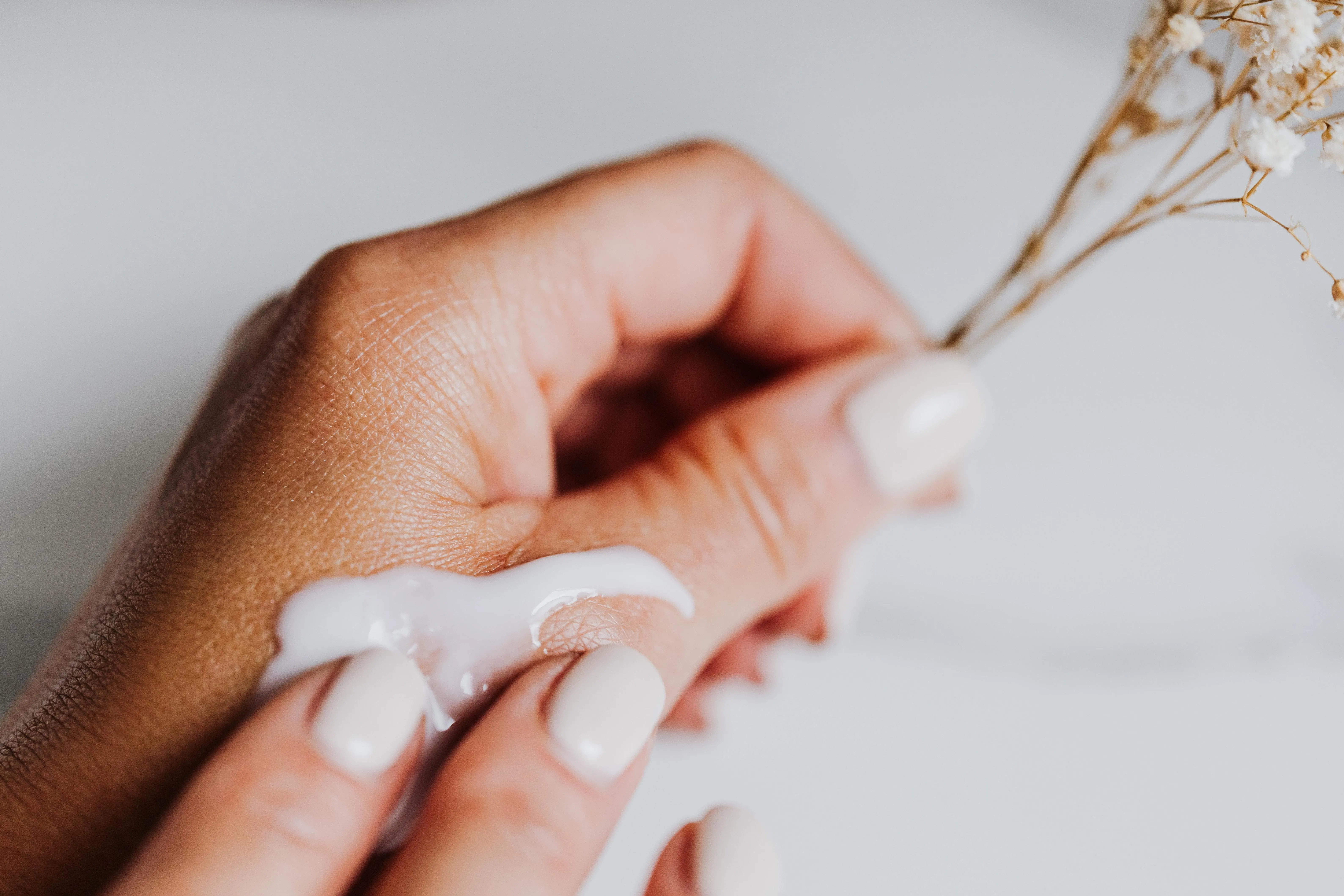 Hand mit Handcreme drauf hält Pflanze