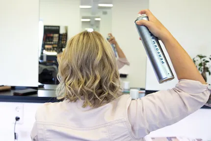 Frau fixiert Beach Waves mit Haarsprray